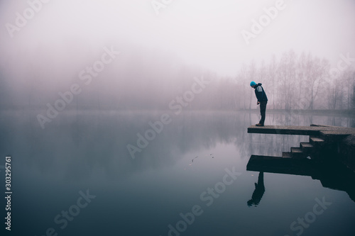 Man standing on a deck above a misty lake. Depression and suicide concept.