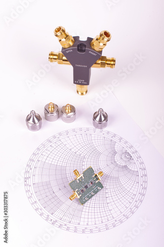 RF mixer electronics PCB in front of Smith chart and other microwave measurement tools and symbols