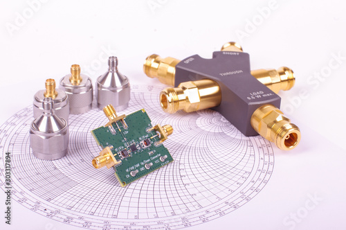 RF mixer electronics PCB in front of Smith chart and other microwave measurement tools and symbols