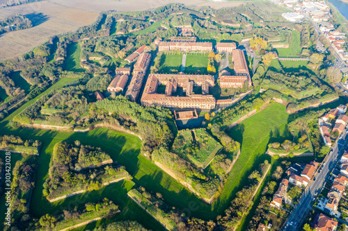 Aerial helicopter view of walls, moats, bastions, earthworks, outworks and barracks of modern six-star hexagon shaped renaissance fortress Cittadella of Alessandria on river Tanaro. Piedmont, Italy