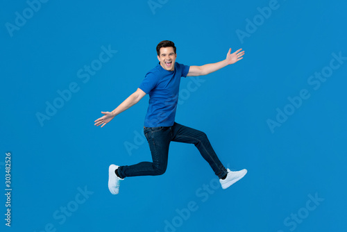 Energetic handsome man jumping and smiling with outstretched hands