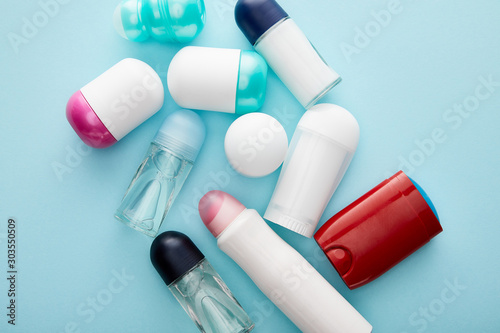 top view of roll on and spray bottles of deodorant on blue background