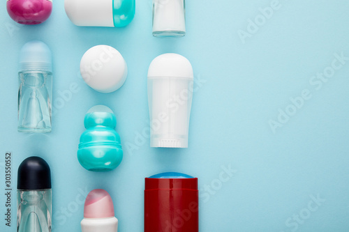 flat lay with roll on and spray bottles of deodorant on blue background