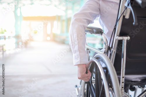 Cropped image of man holding wheelchair outdoors