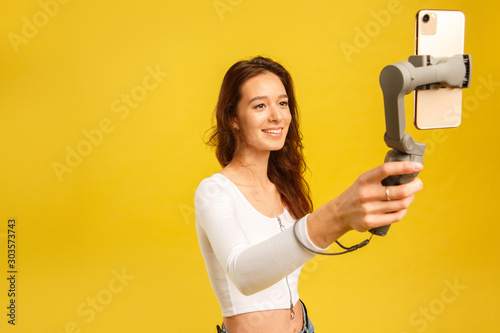 Young blogger girl with three-axis electronic stabilizer gimbal. Makes a selfie and video blog.