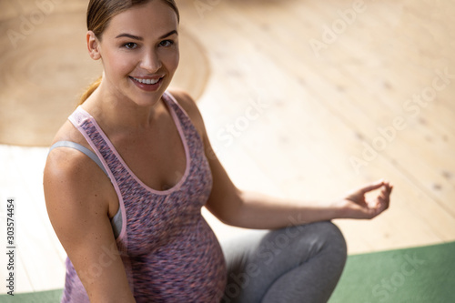 Happy young expectant mother on exercise mat