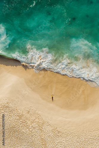 Fantastic drone view green ocean golden beach with a girl Kelingking Beach Nusa Penida Bali Indonesia vertical