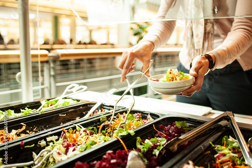 Salatbuffet in einer Kantine, eine Frau bedient sich an einem Salatbuffet