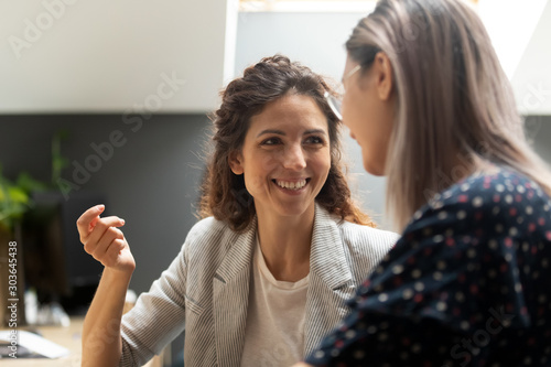 Smiling caucasian female manager communicating with asian colleague.