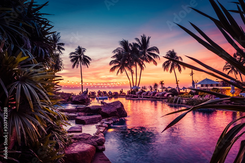 Stunning sunset view with palm trees reflecting in swimming pool in luxury island resort in Thailand