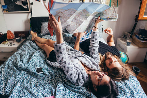 Young couple lying on bed planning travel reading map