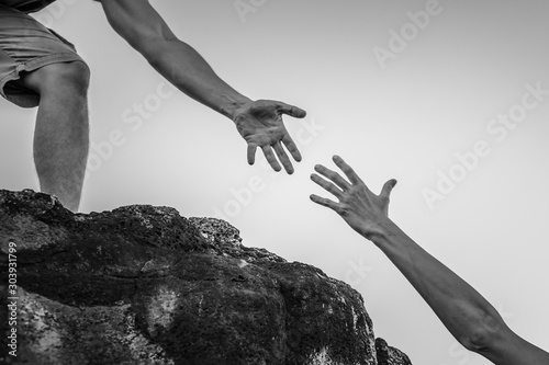 Hand reaching out for help up a mountain cliff. 