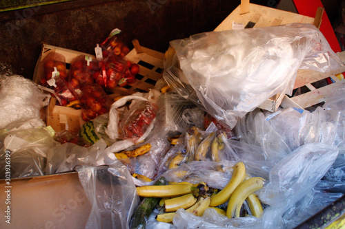  Disgusting trash bin with rotting fruits and plastic bags. An overabundance of products, an environmental problem. Trash for freeganism