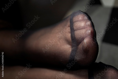 A close up portrait of a foot in black nylon pantyhose with a reinforced toe. The details of the fabric are visible.