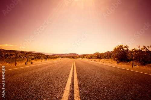 Desolate desert road with mountains with sunflare; western United Stated