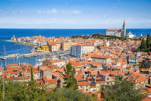 Beautiful aerial view of historic city center of ancient Piran with famous Church of Saint George and Tartini Square on a sunny day with blue sky and clouds in summer, Gulf of Prian, Istria, Slovenia