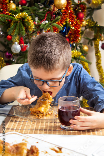 Chłopiec z otwartą buzią podczas jedzenia obiadu. Nakłada do buzi duży kawałek pysznej potrawy. Święta |Bożego Narodzenia.