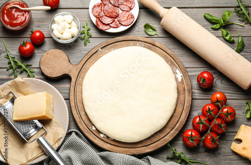 Flat lay composition with dough and fresh ingredients for pepperoni pizza on wooden table