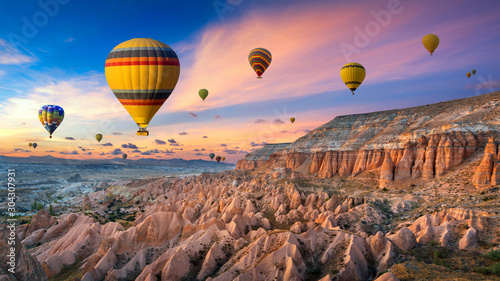 Hot air balloons and Red valley at sunset in Goreme, Cappadocia in Turkey.