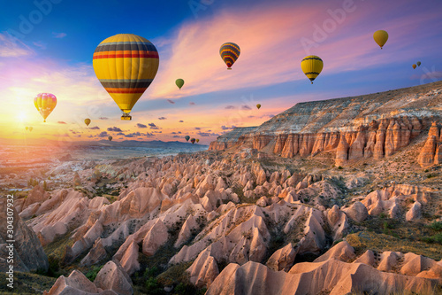 Hot air balloons and Red valley at sunset in Goreme, Cappadocia in Turkey.