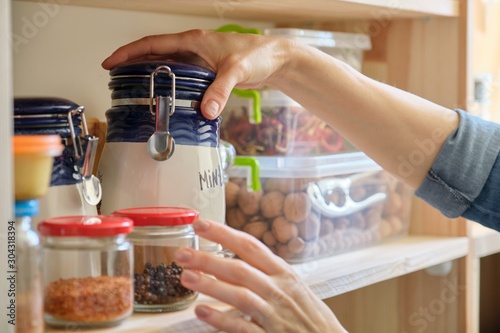 Woman in the kitchen with can of dry mint, food storage, pantry