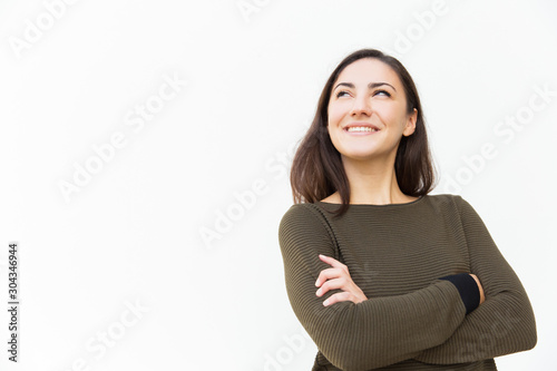 Happy confident beautiful woman with arms crossed looking up at copy space, and smiling. Young woman in casual standing isolated over white background. Promotion concept