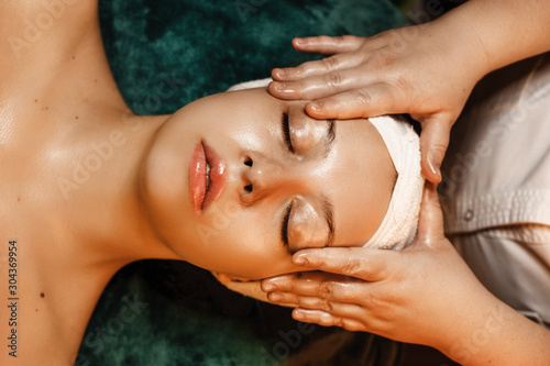 Upper view of a charming woman resting while having skin care routine in a wellness spa center.