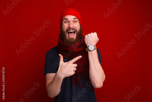 Photo of happy bearded guy, pointing at his newa watch, and delayed at meeting