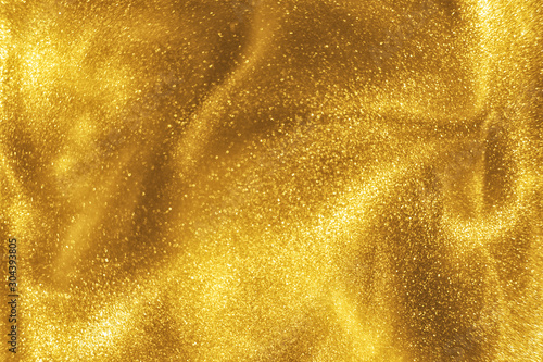 Abstract elegant, detailed gold glitter particles flow with shallow depth of field underwater. Holiday magic shimmering luxury background. Festive sparkles and lights. de-focused.