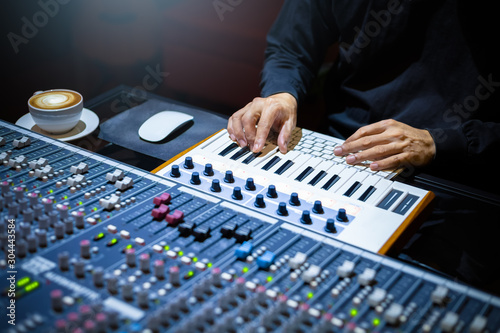 male musician hands playing midi keyboard for recording music on computer in home recording studio. music production concept