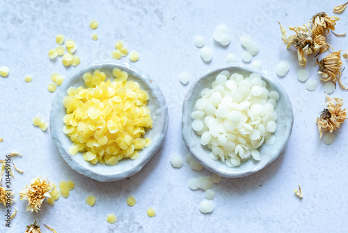 yellow and white cosmetic beeswax pellets in white ceramic bowl for homemade natural beauty and D.I.Y. project.