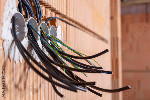 Socket back boxes with wires in a wall. Cabling background. Colorful electrical wires sticking out from electrical sockets hole on brick wall. New electrical wiring installation.