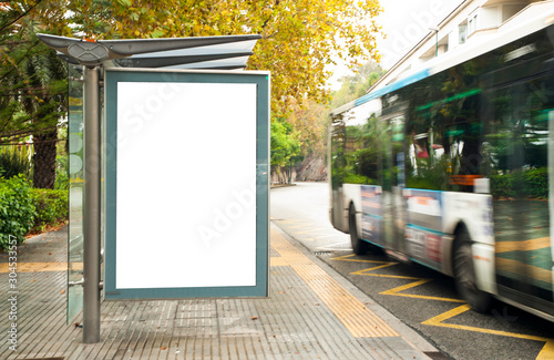 White blank vertical billboard at the bus stop on the city street. In the background of buses and roads. Sketch. Poster on the street next to the road.