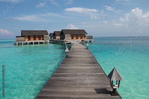 jetty on the sea with water villas bungalows at the end of a wooden walkway, Maldives 