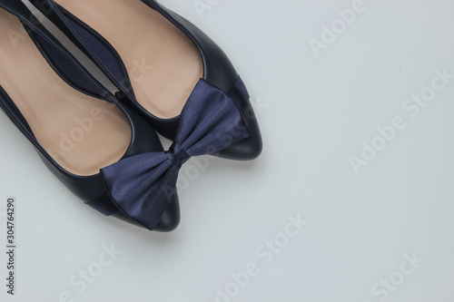 Minimalistic fashion still life. Women's high heel shoes and bow tie on white background.