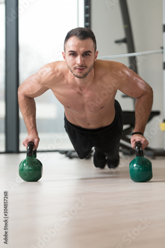 Healthy Man Doing Push-ups On Floor With Kettle-bell