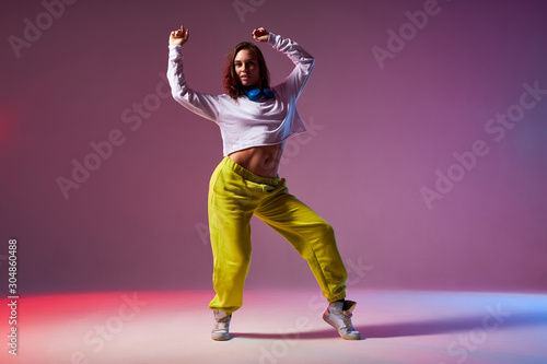 Athletic modern style dancer performing dance element, standing on stage of school dance studio, training hard before competition, sport dancing and urban culture concept
