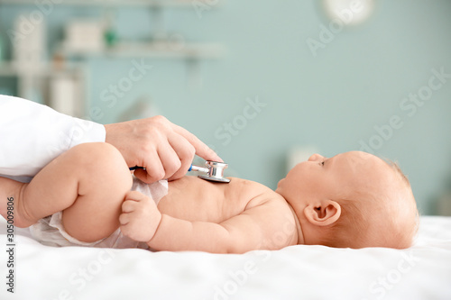 Pediatrician examining cute baby in clinic