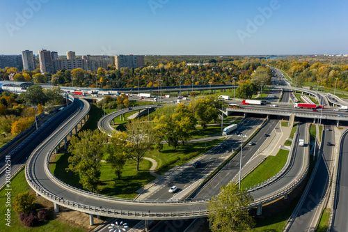 Aerial shot of a big freeway intersection in Warsaw, traffic going fast through many road flyovers. Warsaw, Poland. Drone shot at a highway with a clover junction with bridges and ramps, heavy traffic