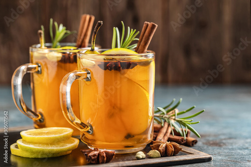 Hot drink cocktail for New Year, Christmas, winter or autumn holidays..Toddy. Mulled pear cider or spiced tea or grog with lemon, pear, cinnamon, anise, cardamom, rosemary.