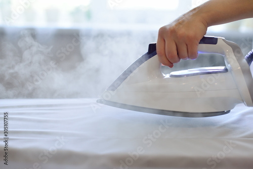 Girl ironing shirt with steam station