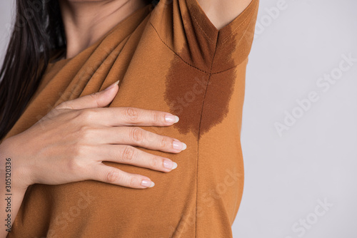 Close-up asian woman with hyperhidrosis sweating. Young asia woman with sweat stain on her clothes against grey background. Healthcare concept.