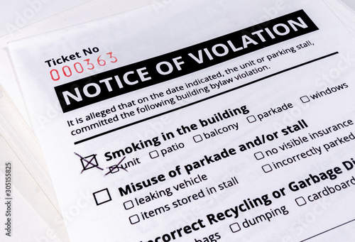 Notice of violation ticket for building bylaws. Close up. No smoking in the building has a check mark. Strata or rental property management tool to warn about smoking, parking and recycling. 
