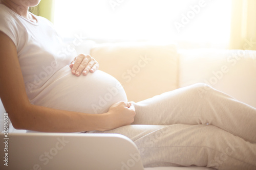 Pregnancy. Happy pregnant woman lying in bed and touching her belly at home