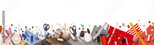 Panoramic view on sewing composition with threads, fabrics, scissors, buttons, needles and other sewing accessories on white background. Long banner, top view, copy space, flat lay, mock up