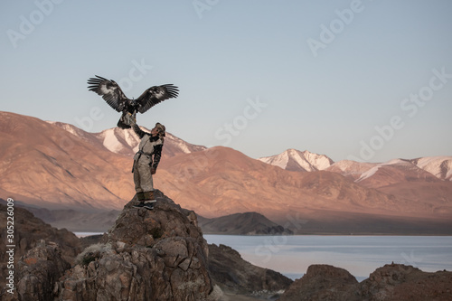 Portrait of a young kazakh eagle hunter with his majestic golden eagle in the steppe. Ulgii, Mongolia.