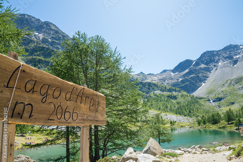 Mountain lake located in italian alps (Arpy lake). Lake signpost in the foreground of the left, the lake and the valley in the background