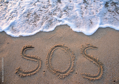 SOS - word drawn on the sand beach