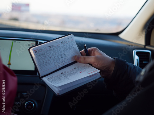 Krasnoyarsk. Russia - March 17, 2019. Notebook with to-do list in the hands of a traveler in a car