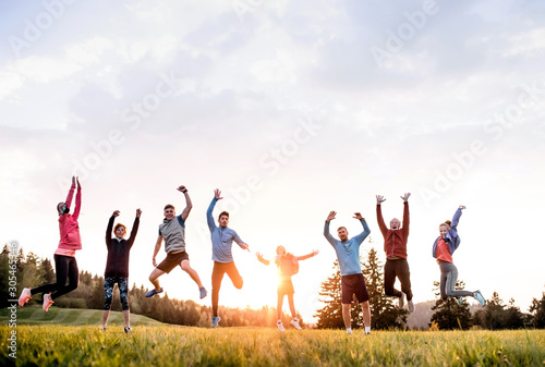 Large group of fit and active people jumping after doing exercise in nature.
